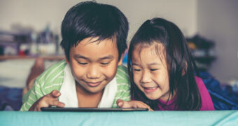 Asian children watching video and playing game on digital tablet
