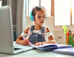 Online training. Child girl in headphones listens to a lesson on
