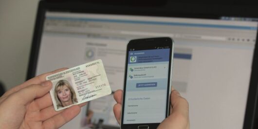 Nutzerin hält Ausweis und Smartphone bereit
